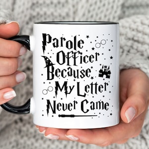 May include: White ceramic mug with a black rim and handle. The mug features a black and white graphic design with the text "Parole Officer Because My Letter Never Came" and Harry Potter themed imagery, including a lightning bolt, a wizard's hat, glasses, and a castle.