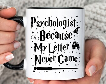May include: White ceramic mug with a black rim and handle. The mug features a black and white graphic design with the text "Psychologist: Because My Letter Never Came" and Harry Potter themed symbols.