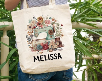 May include: A white canvas tote bag with a floral design featuring a vintage sewing machine, thread spools, and scissors. The bag has the name "Melissa" printed on the bottom.
