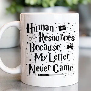 May include: White ceramic mug with a black design that reads "Human Resources Because My Letter Never Came". The design includes a lightning bolt, glasses, a briefcase, a castle, and a wand.