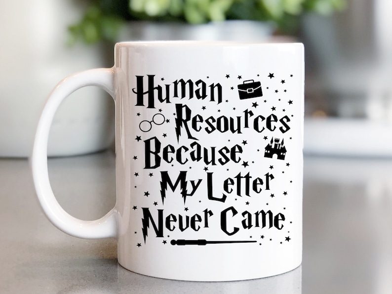 May include: White ceramic mug with a black design that reads "Human Resources Because My Letter Never Came". The design includes a lightning bolt, glasses, a briefcase, a castle, and a wand.