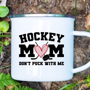 May include: White enamel mug with a black and red graphic that says "Hockey Mom Don't Puck With Me".