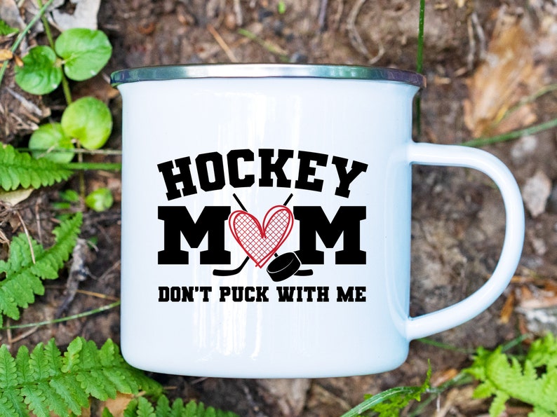 May include: White enamel mug with a black and red graphic that says "Hockey Mom Don't Puck With Me".