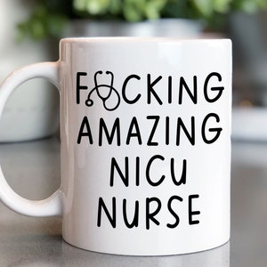 Op de afbeelding: Witte keramische koffiemok met een zwart ontwerp met de tekst "F*CKING AMAZING NICU NURSE" met een stethoscoop afbeelding.