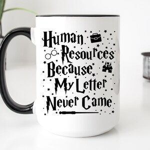 May include: White ceramic mug with a black handle and rim. The mug has a black graphic that says "Human Resources Because My Letter Never Came" with a wand, glasses, briefcase, and castle.