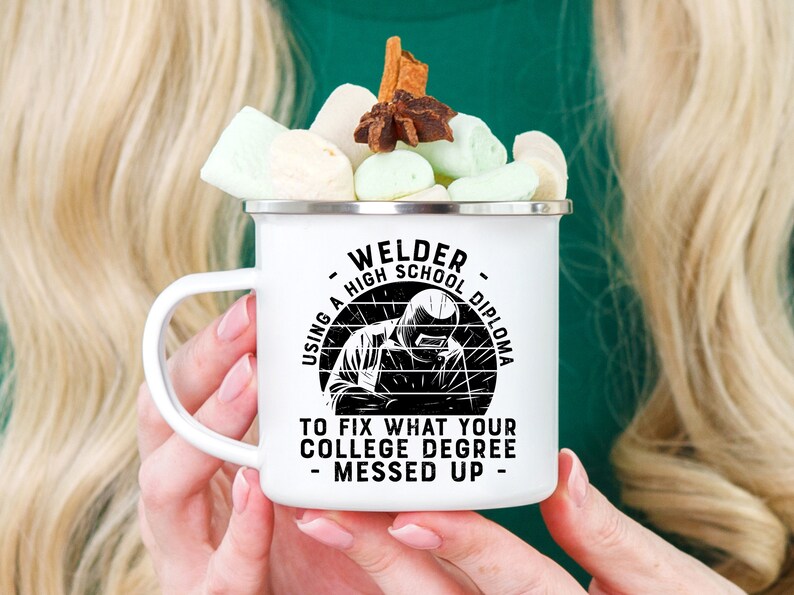 May include: White enamel camping mug with a black graphic that reads "Welder - Using a High School Diploma to Fix What Your College Degree Messed Up - ". The graphic features a welder with a welding mask on.