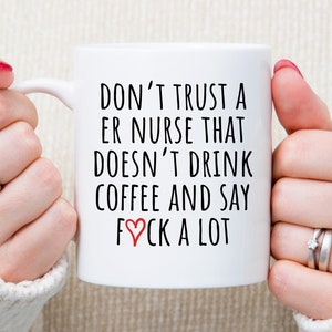 May include: White ceramic coffee mug with black text that reads "Don't trust a ER nurse that doesn't drink coffee and say &hearts;ck a lot".