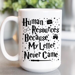 May include: White ceramic mug with a black design that says "Human Resources Because My Letter Never Came" with a lightning bolt, glasses, a briefcase, a castle, and a wand.