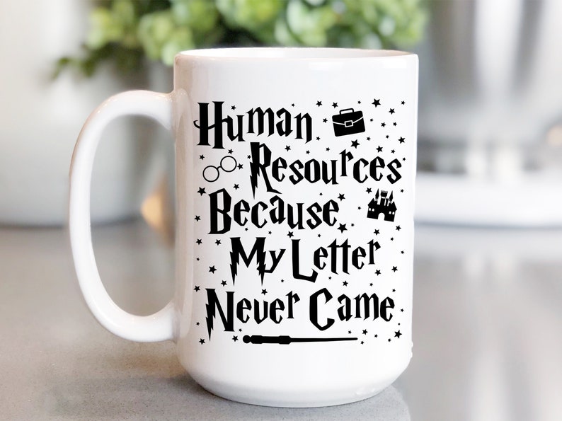 May include: White ceramic mug with a black design that says "Human Resources Because My Letter Never Came" with a lightning bolt, glasses, a briefcase, a castle, and a wand.