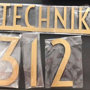 May include: Gold-colored wooden letters spelling "TECHNIK" and the numbers "312" on a white background.
