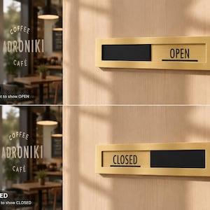 Op de afbeelding: Een goudkleurig schuifdeurbord met de zwarte woorden "OPEN" en "GESLOTEN". Het bord is bevestigd op een lichtbruin houten oppervlak. Het bord geeft aan of een bedrijf open of gesloten is.
