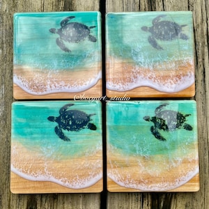 May include: Set of four square wooden coasters with a resin coating. Each coaster features a silhouette of a sea turtle swimming in turquoise water with white foamy waves crashing on a sandy beach.