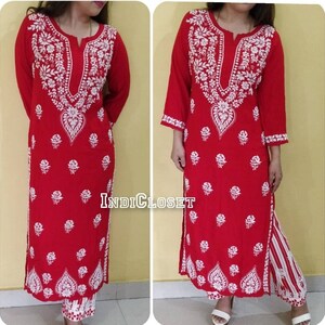 May include: A red and white embroidered kurta with a white floral pattern. The kurta is long and has a V-neck. The pants are white with red and white stripes. The text "INDIcloset" is visible in the image.