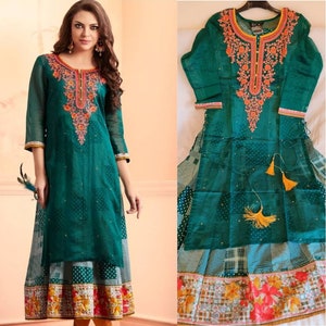May include: A teal green long-sleeved dress with a floral embroidered neckline and a white and black polka dot skirt. The dress has a sheer overlay with a white and black checkered pattern.