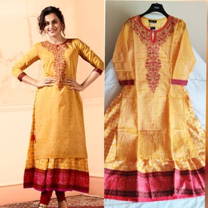 May include: A yellow and red embroidered kurta with a long sleeve and a round neckline. The kurta has a floral design and is layered over a white and yellow printed skirt.