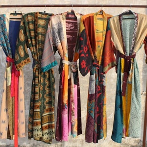 May include: Seven colorful silk robes with patchwork designs hang on a rack. The robes are made of different fabrics and have a variety of patterns, including paisley, floral, and geometric designs.