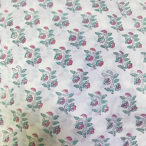 Op de afbeelding: Een witte stof met een herhalend patroon van kleine bloemtakjes. Elk takje bestaat uit groene bladeren en roze bloesems, omlijnd met dunne zwarte lijnen. Het ontwerp is in een consistent rasterpatroon over het textieloppervlak verdeeld.