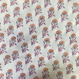 Op de afbeelding: Een lichtcr&egrave;mekleurige stof met een herhalend patroon van kleine, gestileerde bloemen. Elke bloem heeft een oranje bloemhoofd met donkergrijze omlijningen en stelen, geaccentueerd door zachtroze bladeren en stengels in een diagonaal patroon.