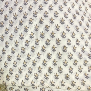 Op de afbeelding: Een witte stof met een herhalend patroon van kleine, gestileerde bloemen in gedempt grijs met gele centra. De bloemenprint is in een consistent rasterpatroon over het textiel verdeeld, wat zorgt voor een uniform en repetitief visueel ontwerp.