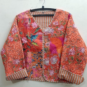 May include: A patchwork quilted jacket with a floral print in shades of orange, pink, and blue. The jacket has a V-neck and a button closure. The sleeves are long and have striped cuffs.