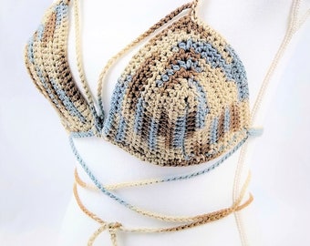 Op de afbeelding: Een gehaakt bikini-topje in een blauwe, bruine en beige kleurstelling. De top heeft een halter-stijl met verstelbare bandjes en strikjes aan de achterkant.