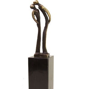 May include: Abstract bronze sculpture of two figures standing close together on a black marble base.