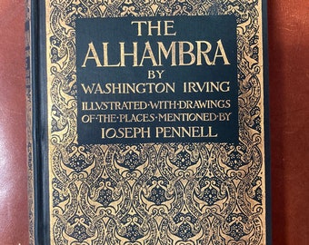 May include: A black book with gold lettering on the cover. The title is "The Alhambra" by Washington Irving. The book is illustrated with drawings of the places mentioned by Joseph Pennell.