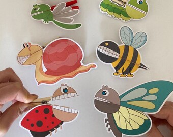 May include: Five colorful bug puppets made from paper with a clothespin attached to each. The bugs include a ladybug, a butterfly, a bee, a snail, and a caterpillar. The title "Bugs Clothespin Puppets" is at the top of the image.