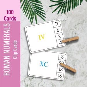 May include: Two white cards with black borders and clip-on clothespins. The top card has the Roman numeral "IV" in yellow and the numbers "11", "6", "2", and "4" in black. The bottom card has the Roman numeral "XC" in blue and the numbers "3", "9", "13", and "16" in black. The cards are on a white marble background with green leaves.