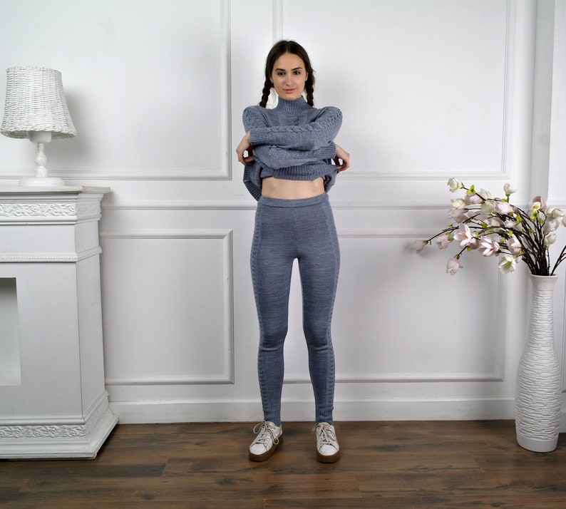 Puede incluir: Una mujer con un su&eacute;ter de punto azul claro y leggings a juego. El su&eacute;ter tiene cuello alto y mangas largas. Los leggings son ajustados y tienen cintura alta.