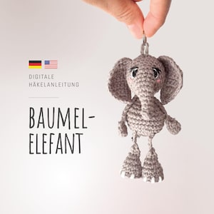Op de afbeelding: Een grijze gehaakte olifant met grote oren, een slurf en kleine witte accenten op de voeten. De tekst luidt: DIGITALE HÄKELANLEITUNG BAUMEL-ELEFANT, vergezeld door Duitse en Amerikaanse vlagiconen, wat duidt op een digitaal haakpatroon.