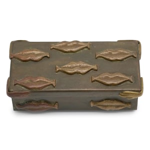 Könnte beinhalten: Eine rechteckige Metallschatulle in Bronzefarbe mit einem wiederkehrenden Muster aus erhabenen, geprägten Lippen auf dem Deckel und der Vorderseite. Die Ecken der Schatulle sind mit kleinen, geformten Metallhänden verziert, die die Kanten greifen.
