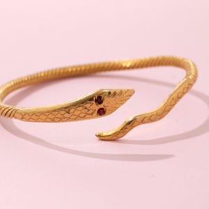 Vintage goudkleurige slangenarmband – rode strassteenogen, diameter 3 inch, verstelbaar