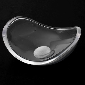 Puede incluir: Un cuenco de vidrio transparente con una forma ondulada y orgánica. El cuenco está diseñado para contener objetos pequeños, como joyas o baratijas.