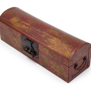 Puede incluir: Una caja rectangular de estilo antiguo con la parte superior redondeada. La caja es de color rojo oscuro con diseños de paisajes dorados. Tiene un cierre y un asa de metal negro, lo que sugiere que es un contenedor para objetos de valor o recuerdos.