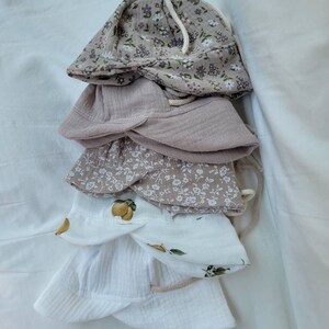 May include: A stack of four cotton sun hats with floral and lemon prints. The hats are in shades of white and beige.