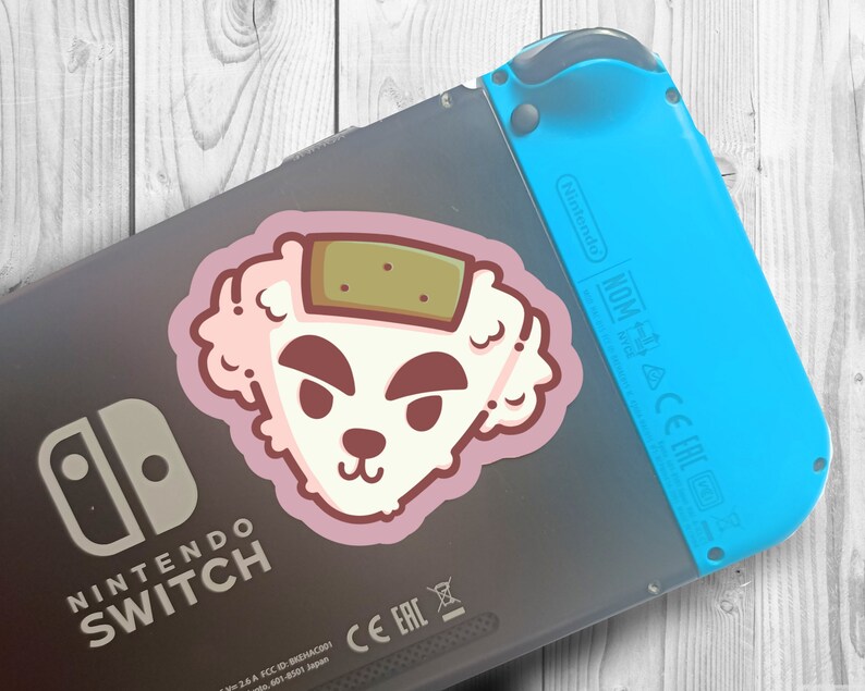 May include: A pink and white sticker of a cartoon dog with a brown patch on its head, attached to a black Nintendo Switch console with a blue Joy-Con controller.