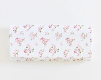 May include: A rectangular box covered in white fabric, adorned with a delicate floral pattern. The pattern features clusters of pink flowers with green leaves, evenly spaced across the surface. The box is presented against a plain white background.