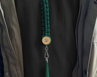 May include: A green paracord lanyard with a 12 gauge shotgun shell charm and a green whistle attached.