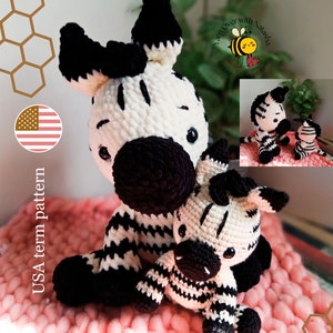 Puede incluir: Un patrón de crochet para un juguete amigurumi de cebra blanco y negro. El patrón está escrito en términos de EE. UU. La imagen muestra dos cebras, una más grande que la otra, sentadas en una manta rosa. La cebra más pequeña está sentada sobre la espalda de la más grande. La imagen también incluye una pequeña abeja con el texto "Yarn Over with Natasha" encima.