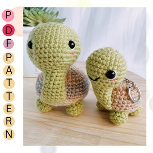 May include: Two crocheted turtle amigurumi toys. The larger turtle is green with a brown shell and the smaller turtle is green with a brown shell and a silver key chain attached.