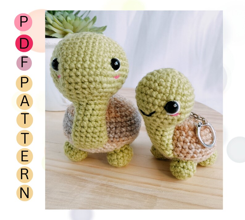 May include: Two crocheted turtle amigurumi toys. The larger turtle is green with a brown shell and the smaller turtle is green with a brown shell and a silver key chain attached.