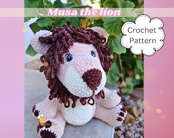 May include: A plush crochet lion toy with a light pink body, a dark brown mane, and dark brown paw pads. The lion has black plastic eyes and a dark brown nose. Text on the image reads Musa the lion and Crochet Pattern.