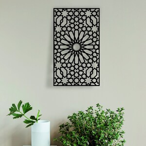May include: Black metal wall decor with a geometric pattern of stars and circles. The design is reminiscent of traditional Moroccan architecture.