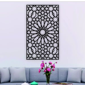 May include: Black metal wall decor with a geometric pattern of stars and circles. The decor is hanging on a white wall above a gray couch with pillows.