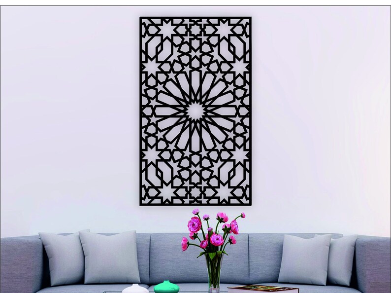 May include: Black metal wall decor with a geometric pattern of stars and circles. The decor is hanging on a white wall above a gray couch with pillows.