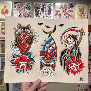 Könnte beinhalten: Tattoo-Flash-Blatt mit drei traditionellen Designs. Eine Fledermaus mit einer roten Rose, eine Fledermaus, die an einem Halbmond hängt, und ein Sensenmann mit einer Sense und einer roten Rose. Die Designs sind in Rot, Blau und Schwarz.