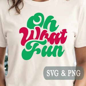 Könnte beinhalten: Ein cremefarbenes T-Shirt mit dem Text Oh What Fun in einer stilisierten, fetten Schriftart. Das Wort Oh ist grün, What ist rot und Fun ist grün. Die Grafik ist mittig auf der Brust platziert. Ein graues Rechteck zeigt den Text SVG & PNG.
