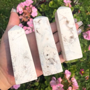 Puede incluir: Tres puntas de cristal de ágata blanca con una textura rugosa y natural. Las puntas están dispuestas en fila, con la punta más grande en el centro.