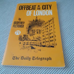 May include: A yellow paperback book titled "Offbeat in the City of London" by Geoffrey Fletcher. The book cover features a black and white illustration of a city street with buildings and a church.